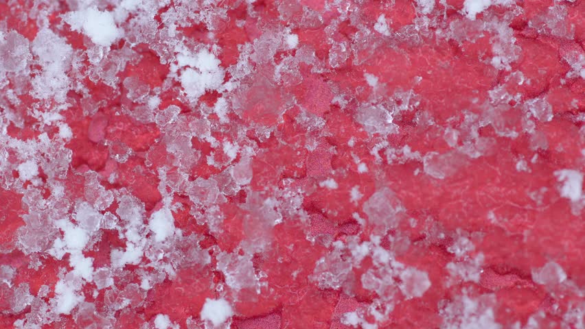 Close-up of melting snow on the hood of a red car in winter