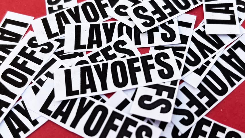 Layoffs concept image with scattered text on red background symbolizing job loss unemployment and workforce reduction