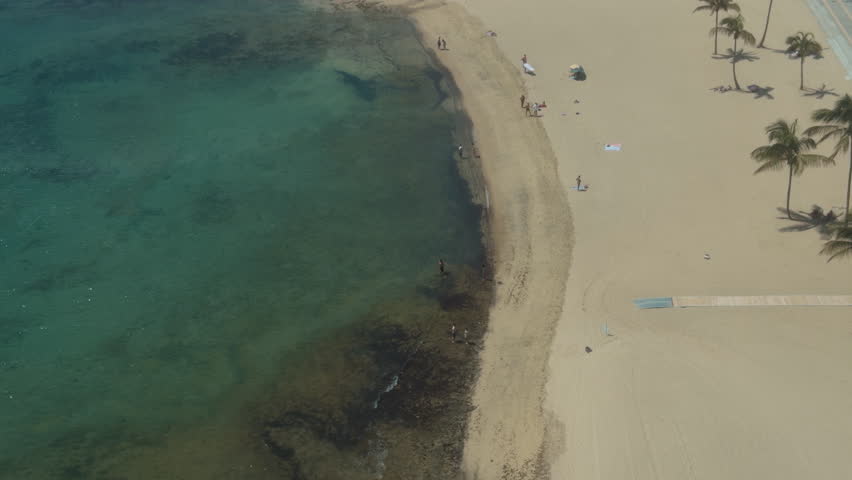 Sun bathers enjoy a day at Aricifi beach, basking in the sun with clear water and soft sand. The beach is a popular spot for tourists.