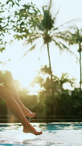 Happiness and joy in summertime, female legs splashing water in swimming pool, woman has fun in luxury hotel in tropical garden. Be carefree and happy, beautiful female body, closeup on graceful feet