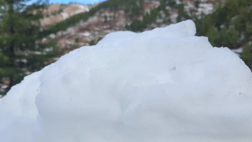 Snowy mound resembling a small hill with a smooth top surrounded by a blanket of white snow in a natural setting 4k