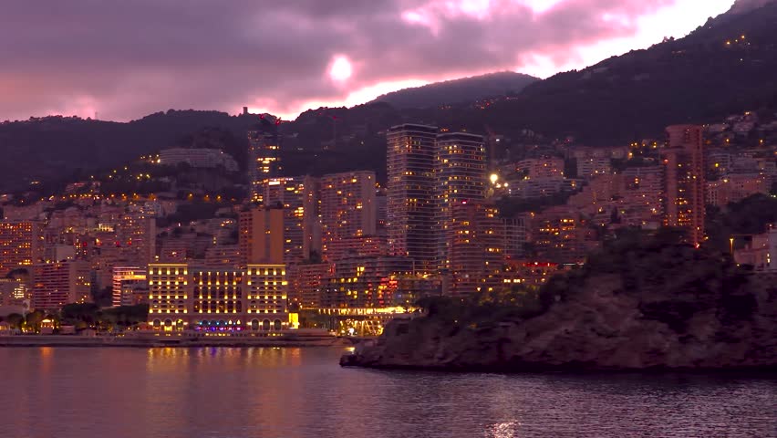 Twilight cityscape of Monaco with illuminated skyline, luxury waterfront buildings and calm Mediterranean Sea, French Riviera, Europe