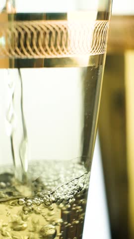 Macro vertical shooting of white wine in glass, bubbles slow motion