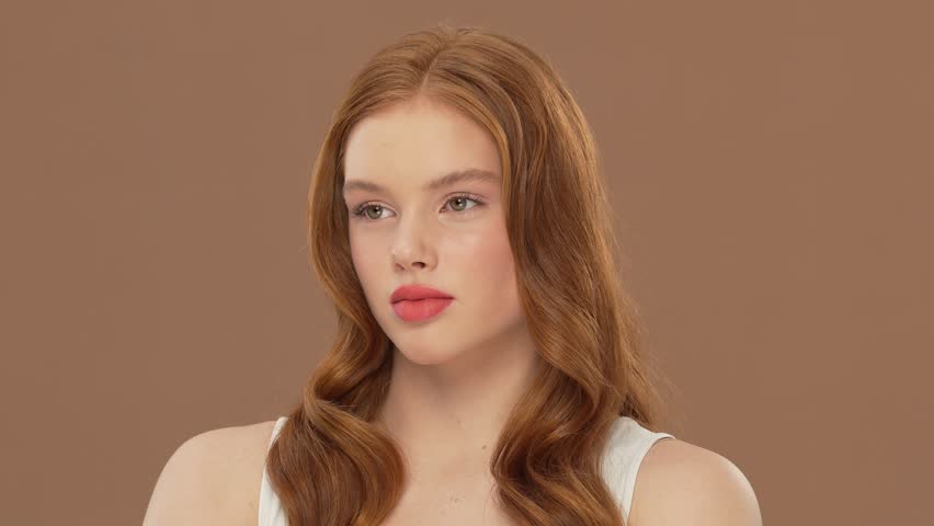 Beautiful teenage redhead girl posing in studio. Portrait of cute female teenager over bright solid background. Close-up face of young Caucasian woman.