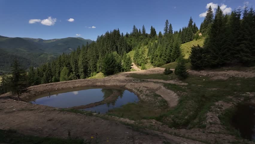 Mountain landscape with small pond and forest, calm natural scenery in summer.