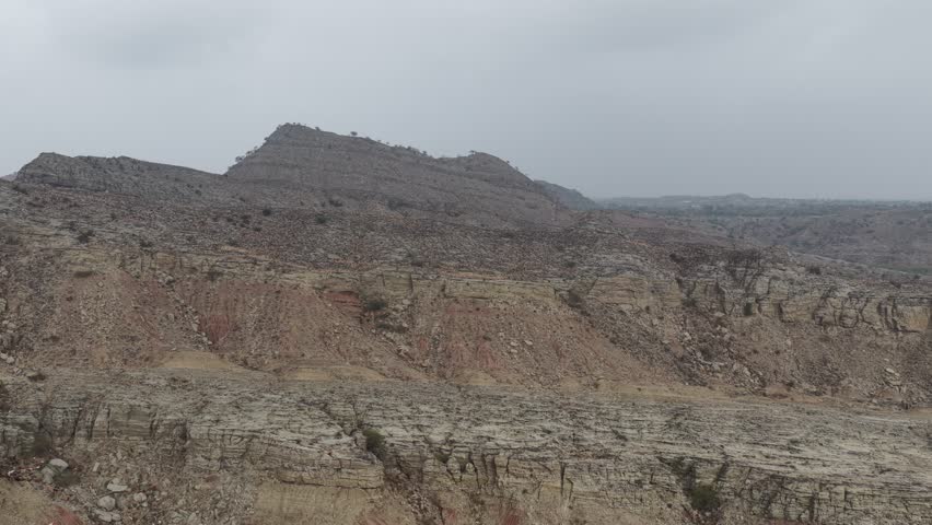 Aerial view of a Dramatic landscape featuring a rocky mountain range with rugged terrain and sparse vegetation under a cloudy sky 4k footage
