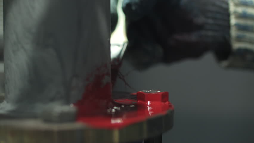 Worker painting metal surface with red paint brush
