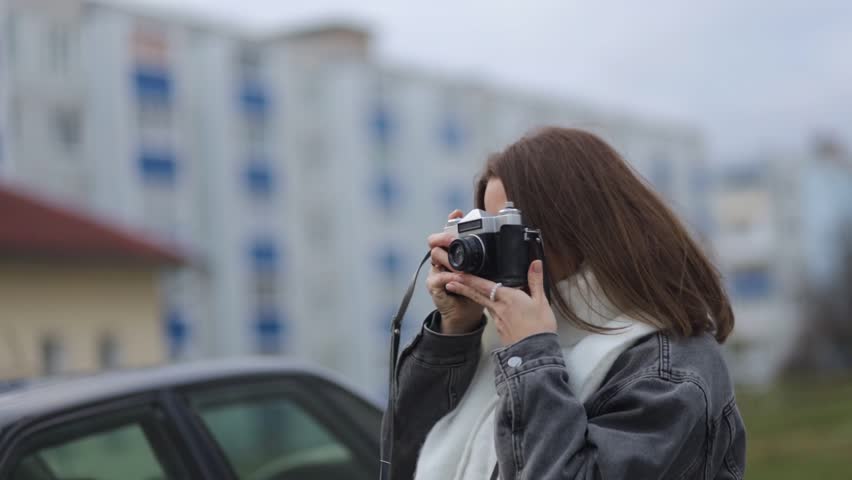 A female photographer takes pictures in the city with a film camera