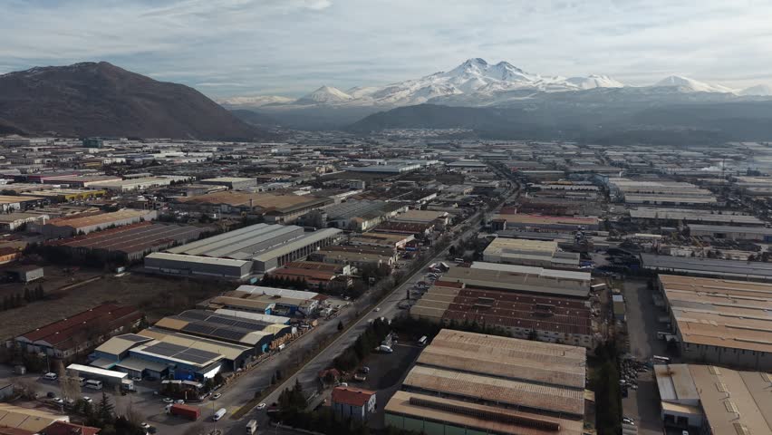 Aerial view of Kayseri Organized Industrial Zone with Mount Erciyes in the background, showcasing large scale manufacturing facilities and industrial infrastructure in central Turkey.