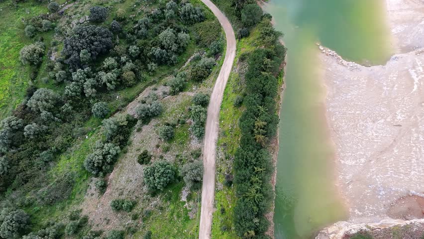 Nature trail along a riverbank with lush greenery and winding paths in a serene landscape