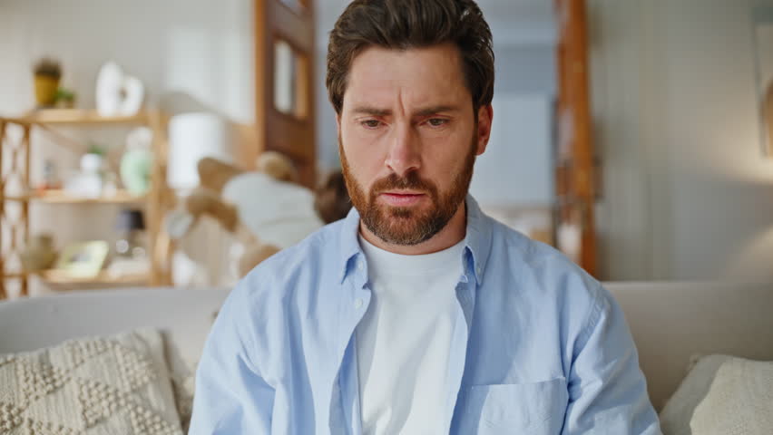 Father freelancer reacting noice home sofa closeup. Shouting kids distracting father playing soft toys running around living room couch. Nervous dad businessman trying concentrate feeling distraction