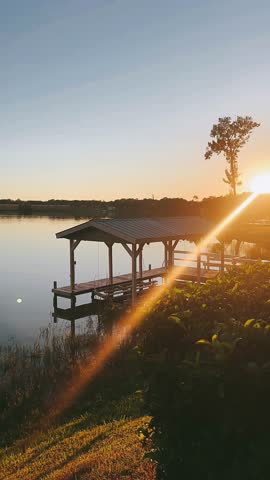 quiet lakeside dock with covered boat slip at golden hour beside calm water and wide open sky