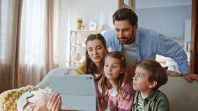 Happy relatives looking webcam tablet greeting at online meeting home closeup. Smiling bearded father video calling with preteen kids and wife together at comfortable couch. Modern family technology - Powered by Shutterstock - Get 15% off with code: PIKWIZARD15