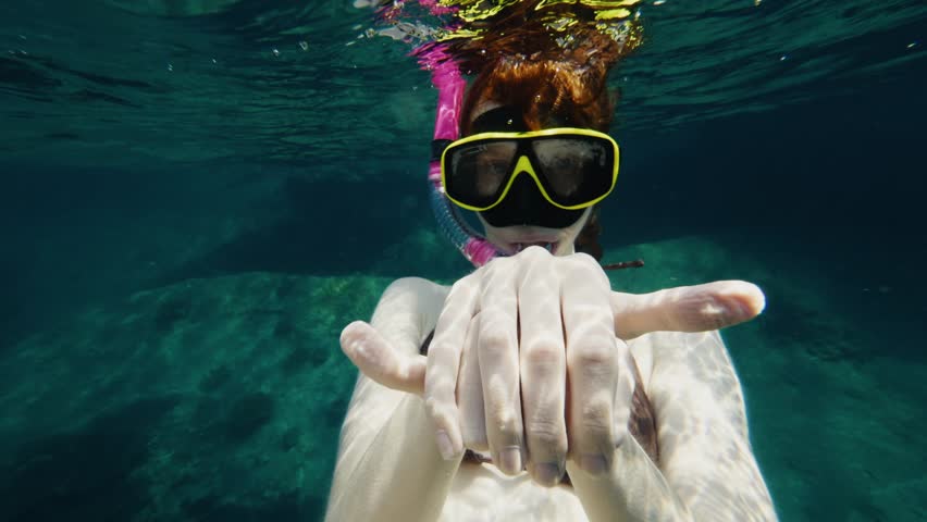 Woman with snorkeling mask sinking into the sea