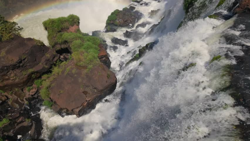 Iguazu Falls showing immense water plunging through a verdant rainforest, creating a colorful rainbow, Argentina