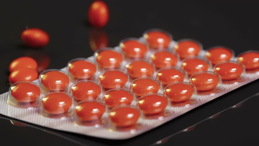 Red Sugar-Coated Pills tablets falling onto blister pack and colliding suggesting medication or medicine pharmaceutical themes, health, healthcare, treatment, and medical care
