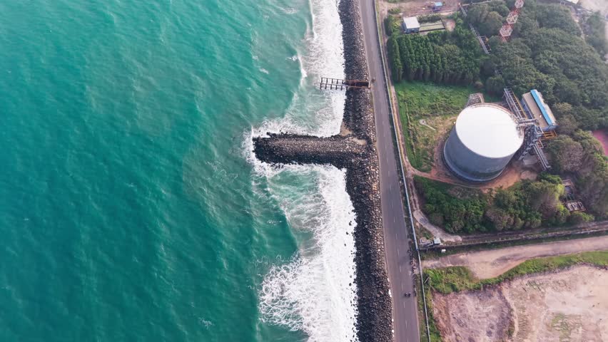Aerial view of coastal highway along ocean waves and rocky shoreline across
