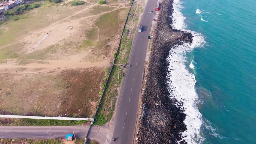 Aerial view of coastal highway along ocean waves and rocky shoreline across