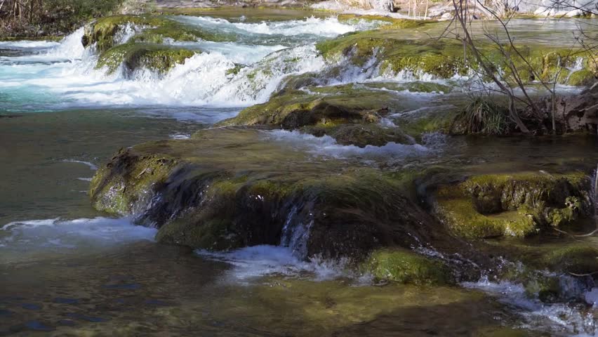 Water flowing in various directions down a river stream, over large flat boulder surfaces.
