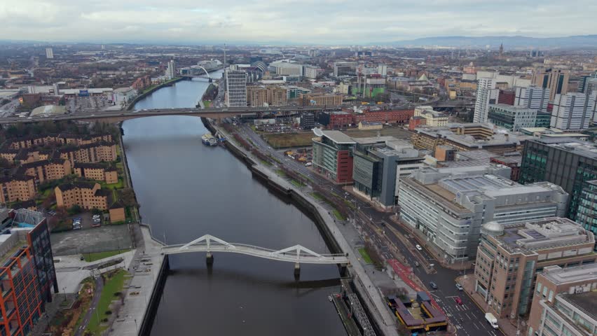 Cinematic aerial drone fly toward Kingston Bridge spanning the River Clyde in Glasgow, Scotland, with expansive urban skyline and city architecture.