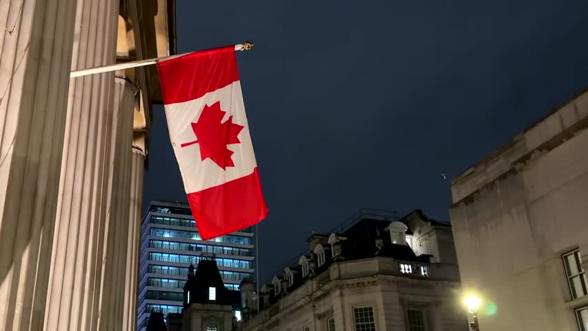 Street View Of A Canadian Flag On The Embassy Building At Night In London, United Kingdom.