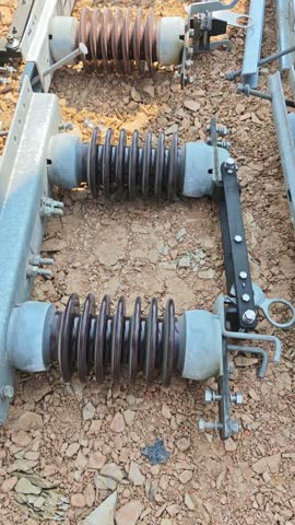 Tilt up video of electrical disconnect switch on ground. High voltage isolator equipment with brown porcelain insulators for installation.
