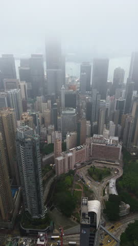 Vertical drone shot rotating over the central district of Hong Kong, foggy day
