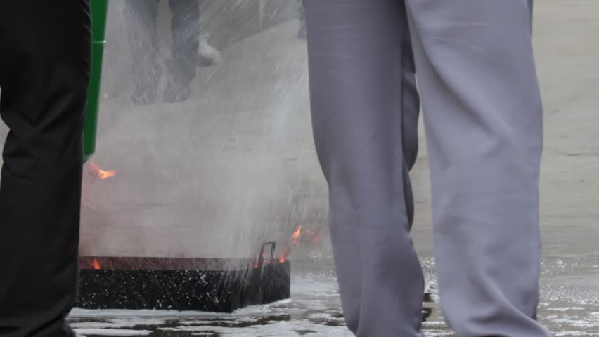 Fire extinguisher hose safety training program emergency drill at workplace, worker practice foam spray response on wet concrete pavement