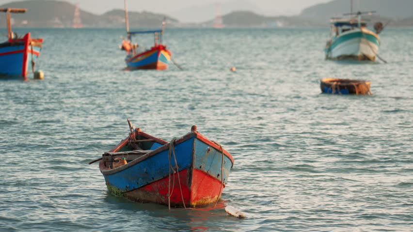 Colorful fishing boats floating on water at sunset in a coastal area