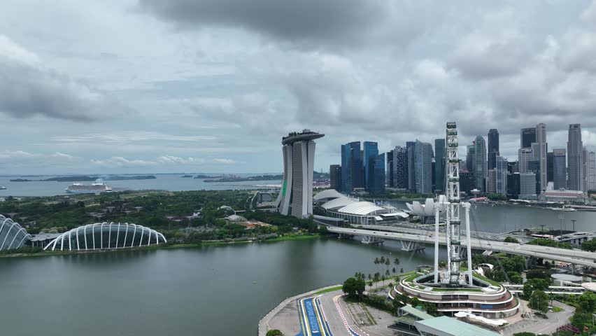 Drone footage panning around the Singapore Flyer ferris wheel, showcasing the modern skyline and waterfront cityscape from an aerial perspective in Singapore.