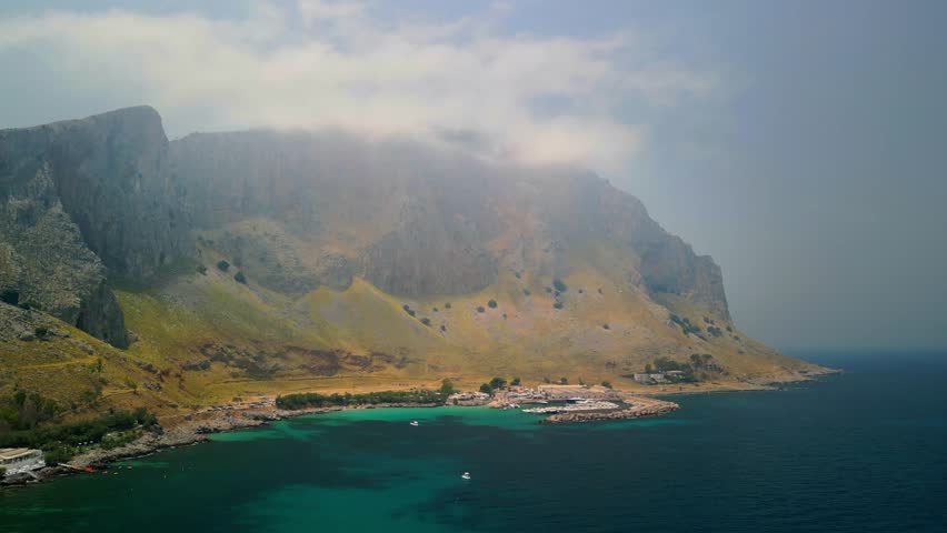Drone view of Terrasini’s harbor area with rows of boats and protective piers.
Cinematic aerial footage showcasing Terrasini as a classic Sicilian seaside town.
Aerial drone shot revealing Terra