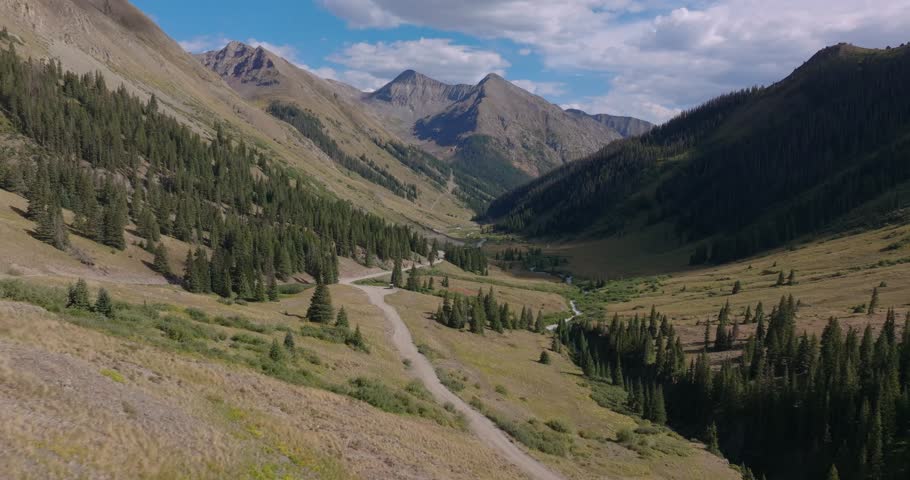 Broad alpine valley with winding road and creek in San Juan Mountains, Trans America Trail, Colorado, USA