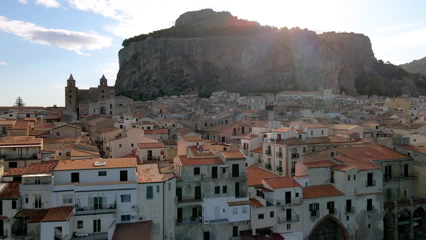 Discover the beauty of Cefalu, Sicily, with its picturesque rooftops under the warm sun. The iconic cliff stands proud, while the ancient buildings reflect rich history. Sicily Italy