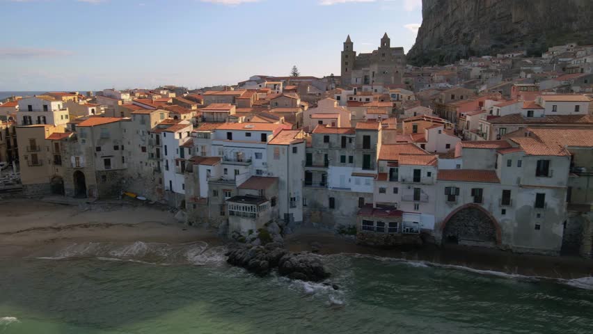 Wander through the picturesque streets of Cefalu, where vibrant houses line the shore and a majestic mountain looms above. Experience the enchanting atmosphere of this historic town in Sicily.