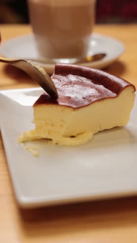 Person scooping a piece of creamy basque burnt cheesecake from a white plate