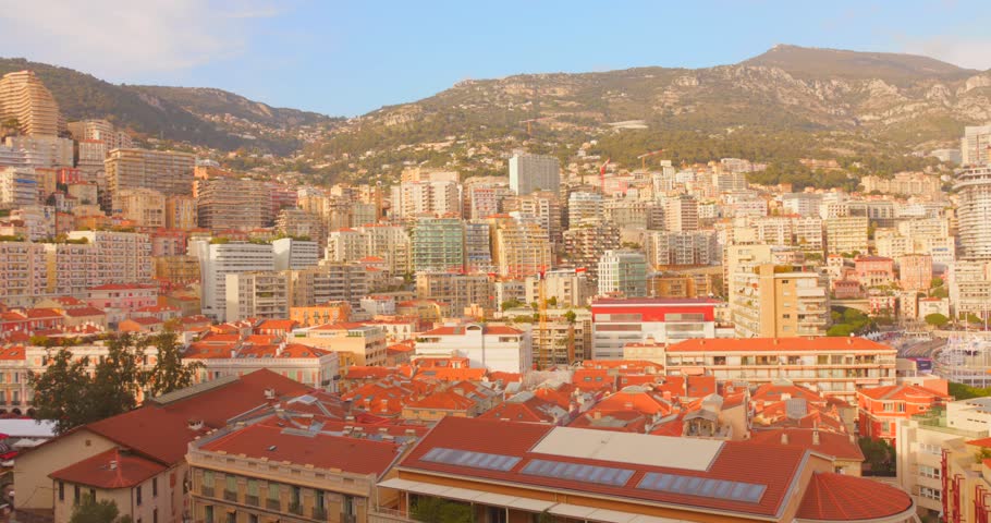 Panoramic view of Monaco city with dense urban buildings framed by surrounding mountains and coastal landscape.