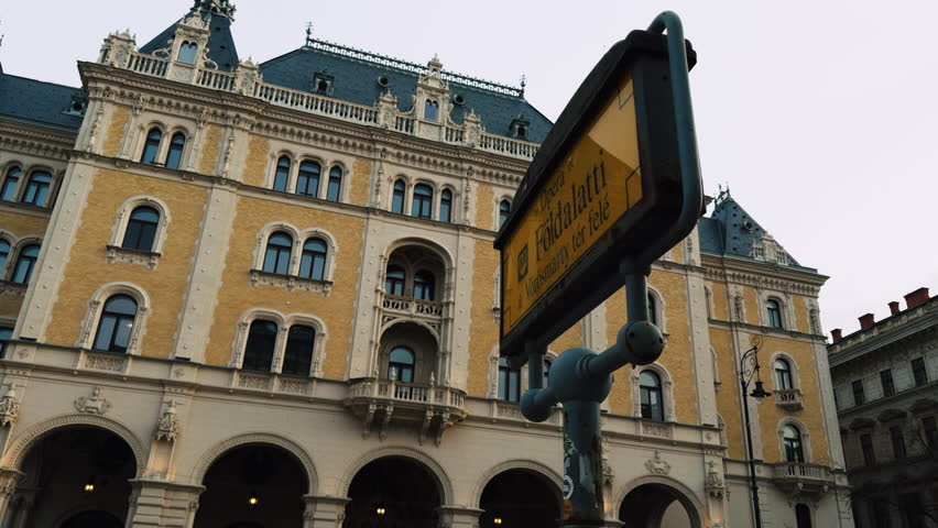 Exterior view of a historic hotel near the Opera metro station in Budapest, featuring ornate architecture and a classic subway sign reflecting everyday urban travel.