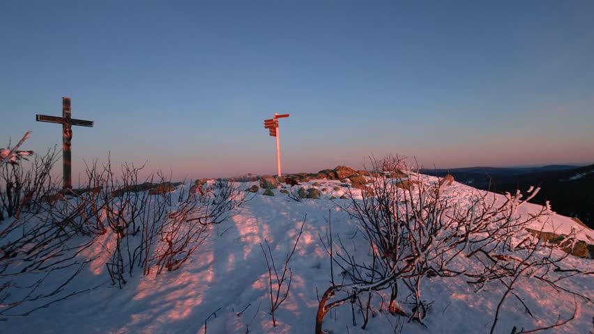 Slow camera movement reveals snowy forest ridges and misty valleys glowing in golden morning light during winter dawn