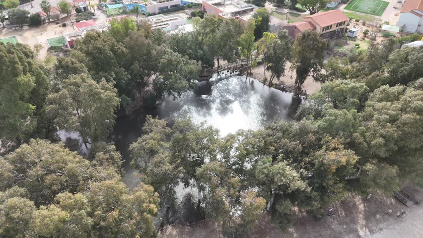 Aerial 4K view of a winter pond with reflections and green landscape