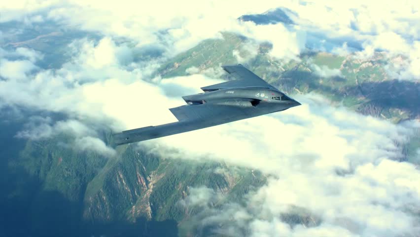 B-2 Spirit Stealth Bomber Flying Over Clouds and Green Forest Landscape