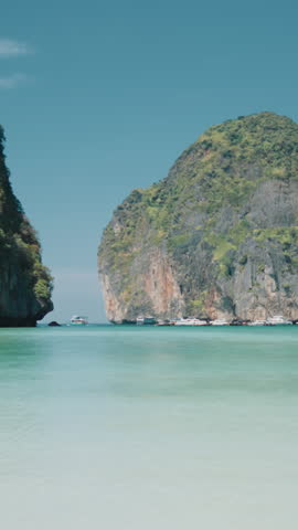 Rest in paradise in summer, unique seaview with famous thai Phi Phi Archipelago, calmness and solitude. Cinematic vertical shot from sandy beach in Maya Bay, visit Thailand and feel happiness and joy