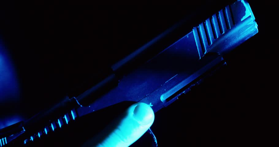 Cinematic close-up of a hand loading a pistol under blue light, symbolizing danger, tension, and a high-risk situation.