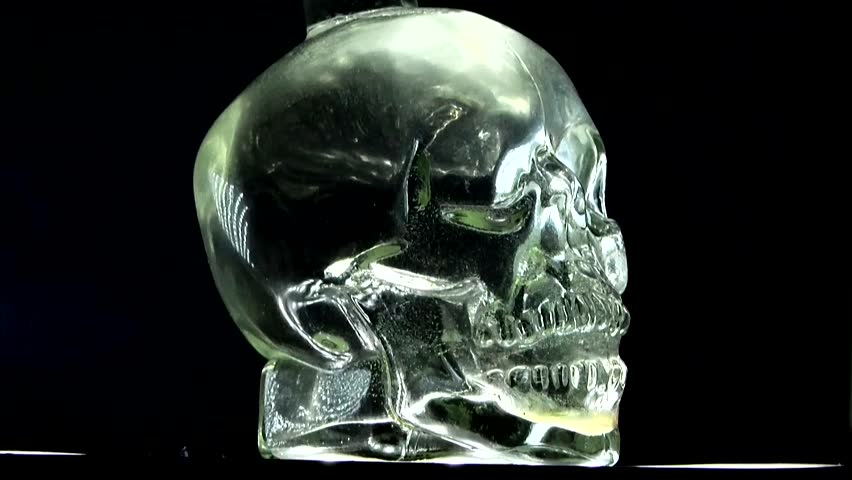 A skull-shaped glass with water on a black background