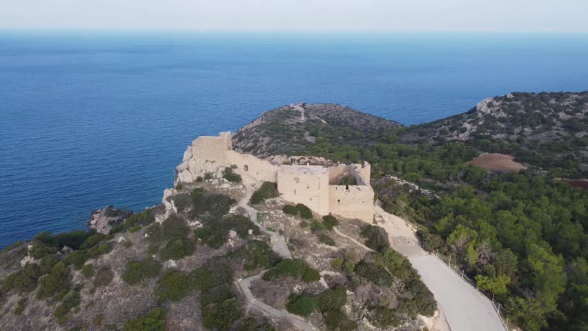 Aerial view flying forward toward Kritinia Castle on the island of Rhodes, Greece with surrounding landscape and coastline visible