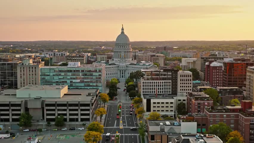 Aerial sunset view of the iconic Wisconsin State Capitol in Madison with golden light illuminating the historic dome and city skyline.
