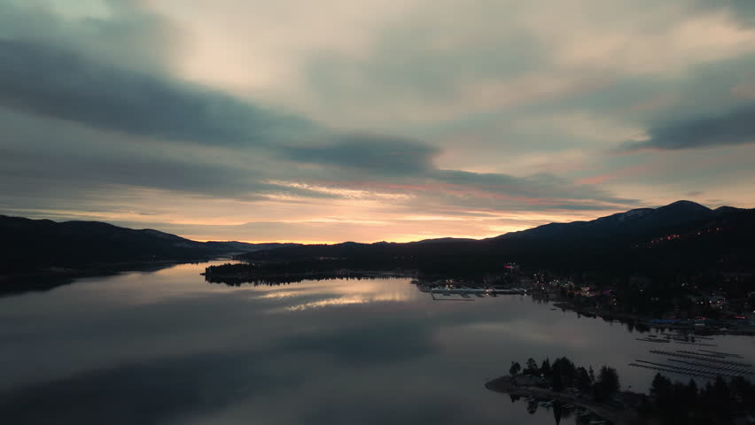 Soft dawn light over lake with pastel sky and still water reflecting forested hills quietly