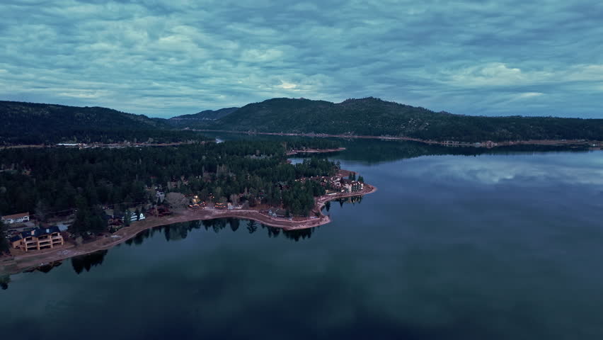 Aerial view of Big Bear Lake shoreline with mountain homes and forest landscape below