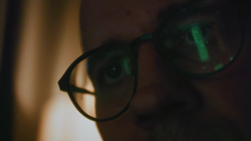 Man stock trader in home office. Male analyzes terminal, trades stocks on crypto market. Quotes from Bitcoin Ethereum, or funds. Candlestick or trading charts, price action are reflected in glasses.