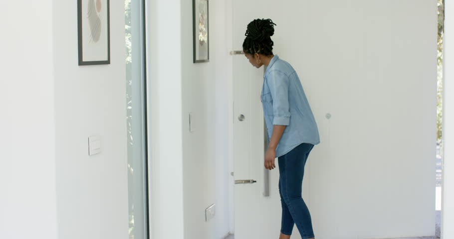 Mother opening door at home to teenage daughter arriving with backpack phone, greeting and hugging. Parent, teen, embrace, entryway, doorway, daylight, sunlight