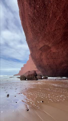 A stunning natural rock arch formation on Legzira Beach, Morocco, under a clear blue sky. Breathtaking nature, a peaceful scene. Vertical video